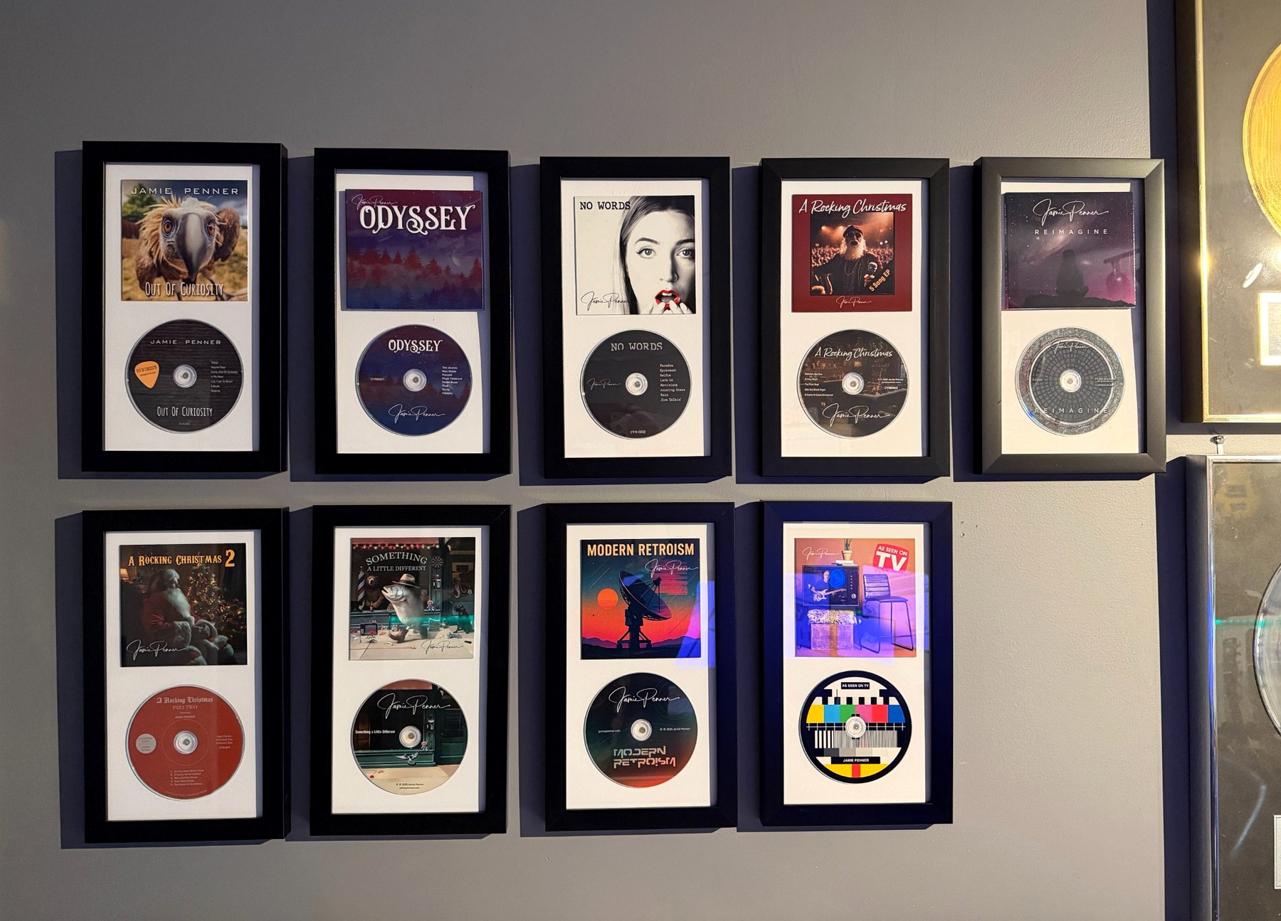 Nine framed Jamie Penner CD releases on the studio wall, with the edge of a gold record visible at right